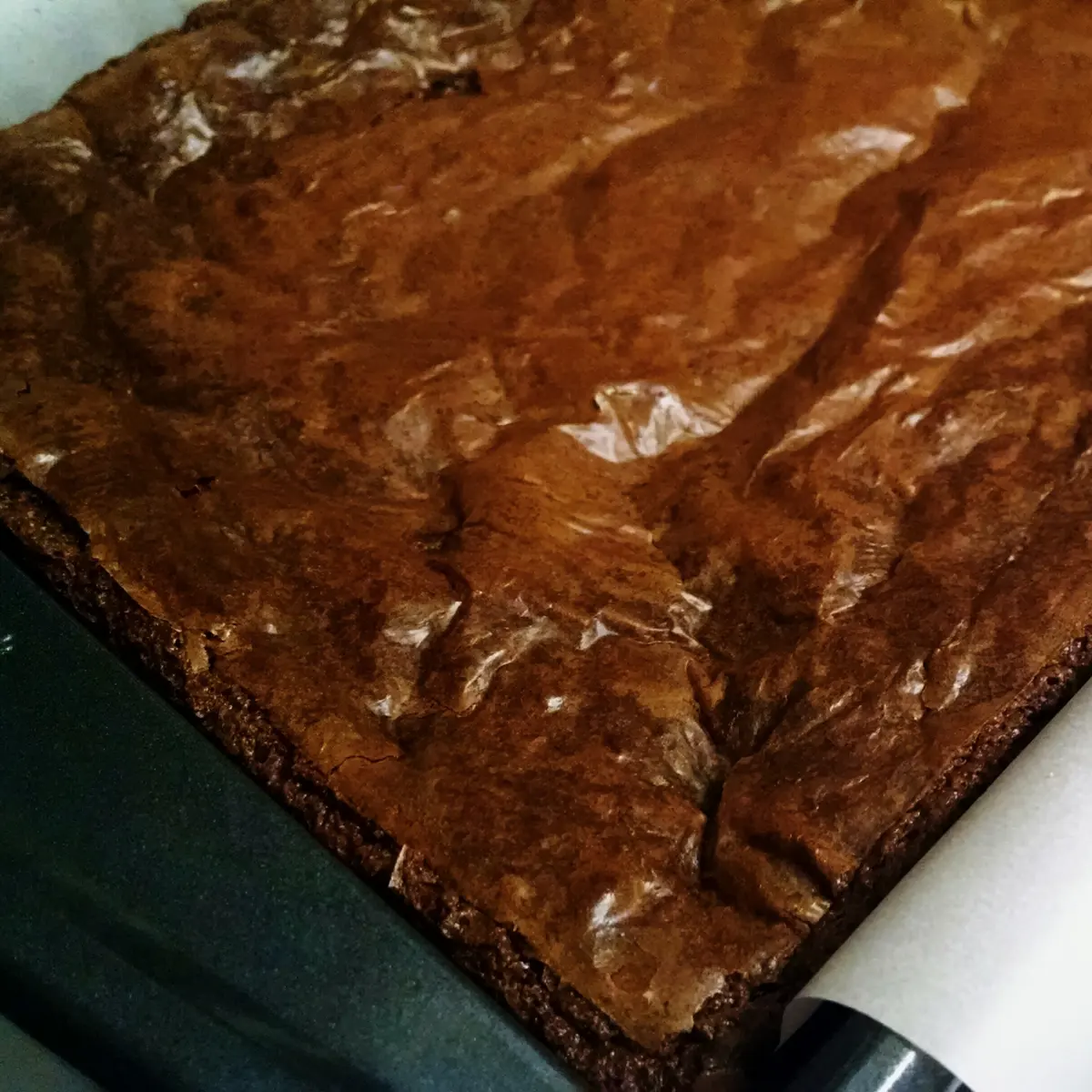 Tanda de brownies recién horneada en el molde, con la superficie cuarteada y el borde firme de la masa
