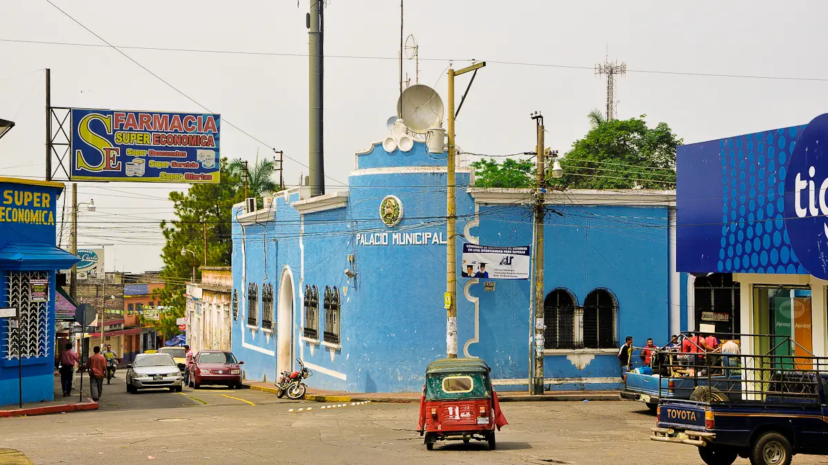Palacio municipal de Mazatenango, de fachada azul, con calles y vehículos