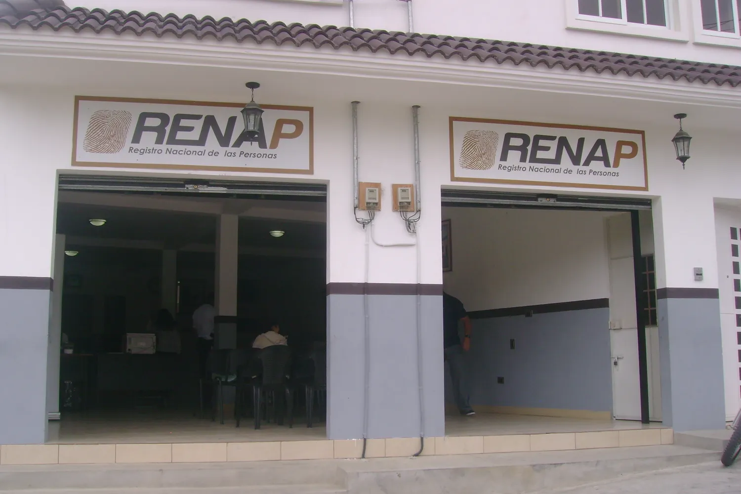 Fachada de una oficina del Registro Nacional de las Personas con dos rótulos de RENAP y la puerta abierta hacia la sala de atención