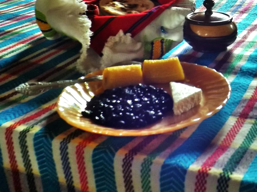 Desayuno servido en una mesa de San Juan la Laguna: frijoles, queso fresco, plátano frito, tortillas y una taza de café