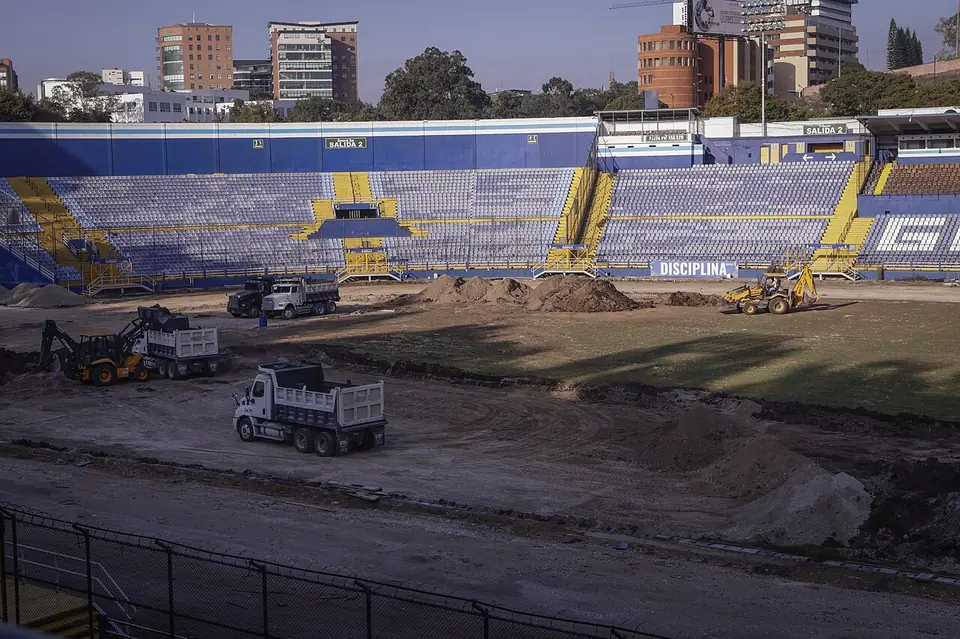 Trabajos de remozamiento en el Estadio Doroteo Guamuch Flores con maquinaria y graderías al fondo