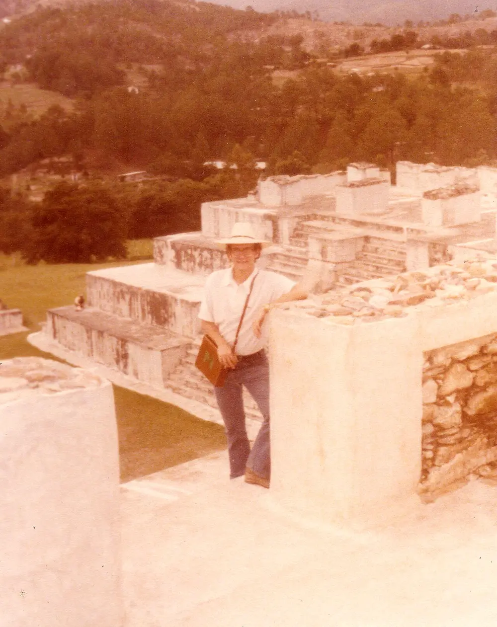 Visitante de pie sobre las ruinas de Zaculeu en 1979, con muros blancos de piedra y colinas al fondo