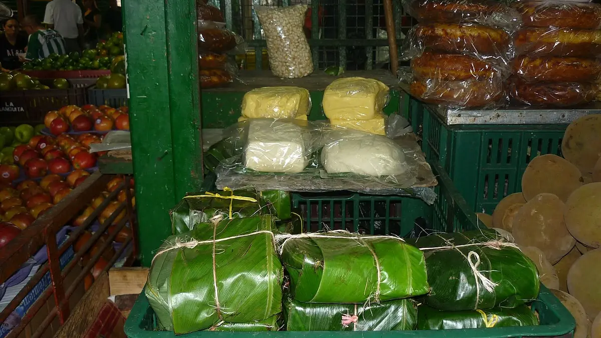 Puesto de mercado con quesos blancos envueltos en hojas, sobre un mostrador