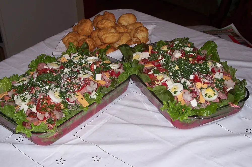 Dos fuentes de fiambre con lechuga, huevo, queso y verduras, junto a trozos de pan