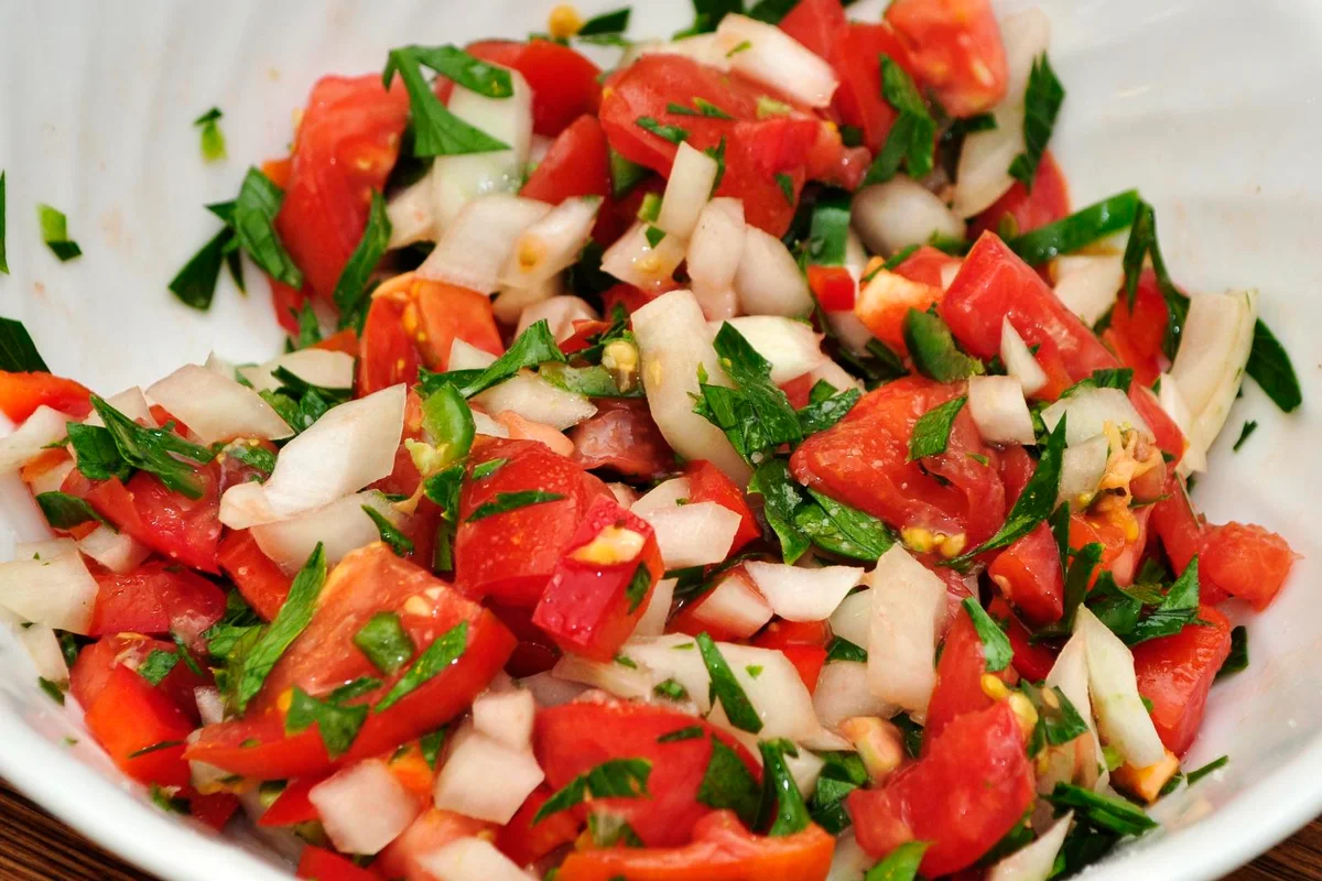 Pico de gallo recién mezclado en un tazón blanco, con tomate, cebolla y cilantro