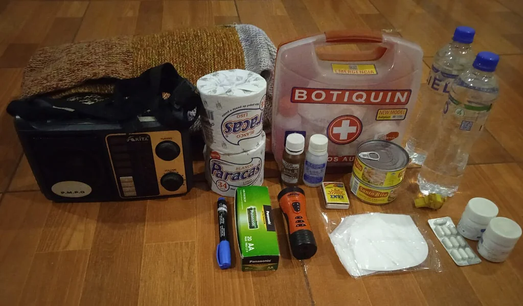 Botiquín, linterna, radio, botellas de agua y otros artículos de emergencia sobre una mesa
