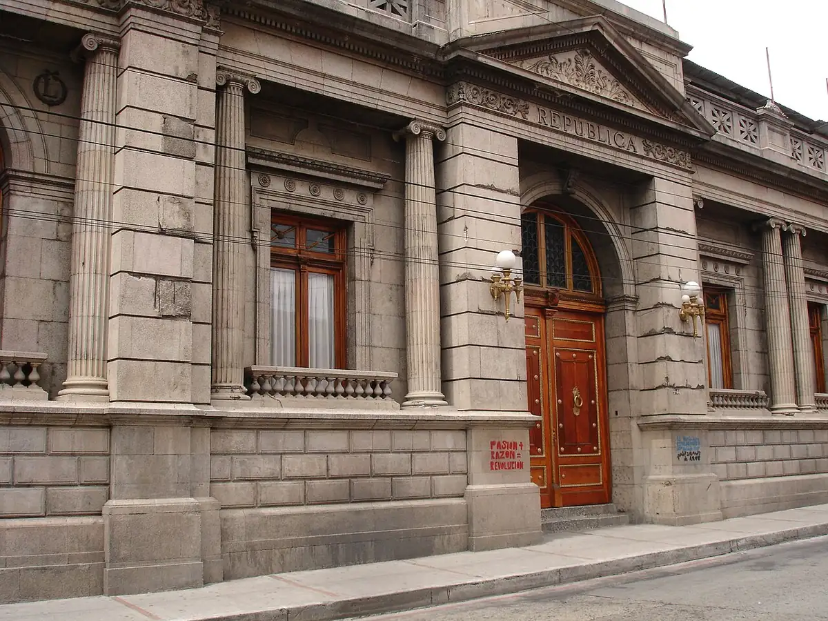 Fachada de piedra del edificio del Congreso de la República, con columnas y una puerta de madera