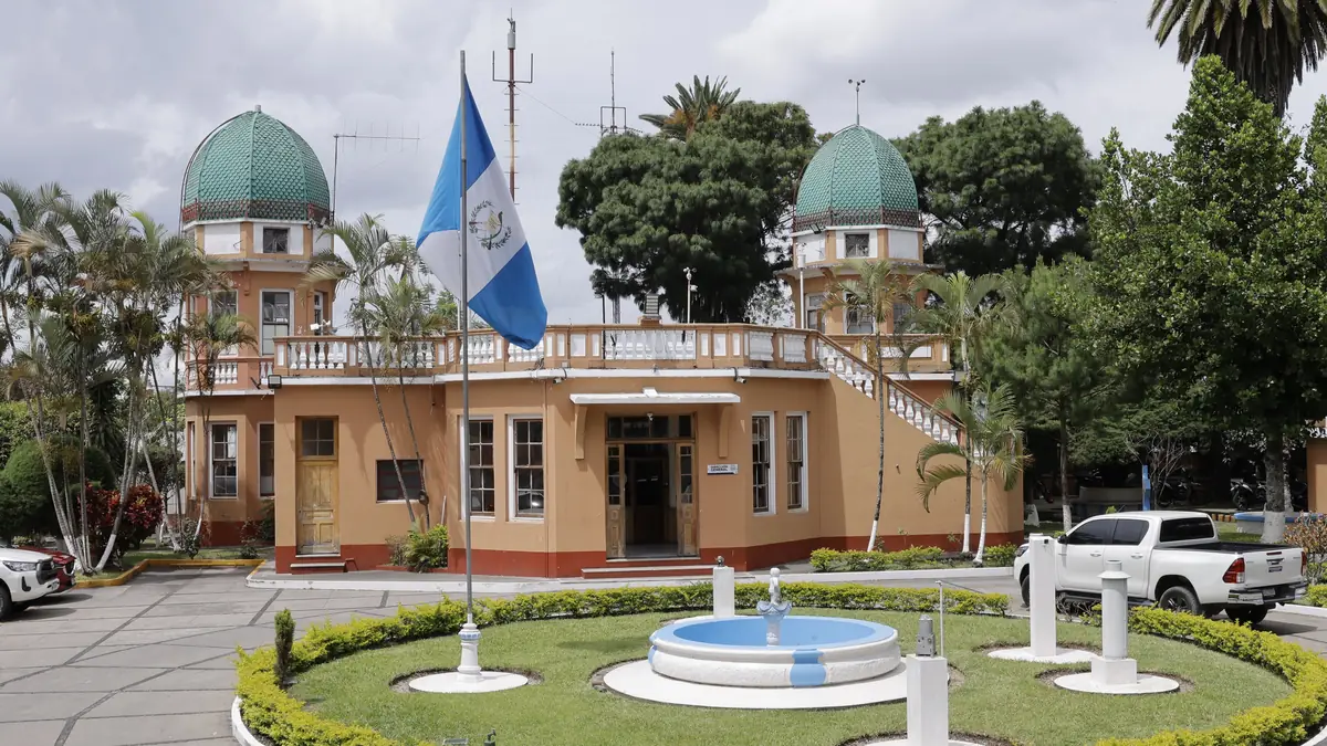 Edificio del Insivumeh con la bandera de Guatemala al frente y palmeras alrededor