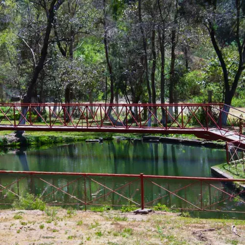 Puente rojo sobre una laguna natural dentro del Balneario Pachitac