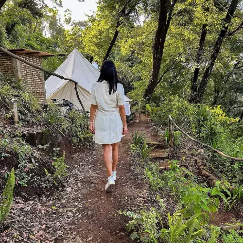 Huésped camina por un sendero de Casa Blanca Glamping entre carpas y vegetación