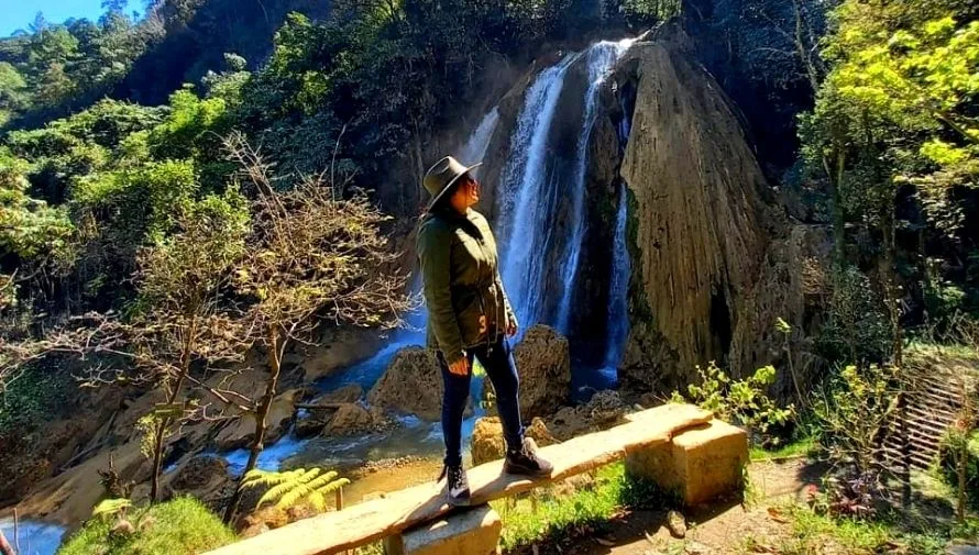 Visitante frente a una cascada de Santa Avelina junto a un puente de madera