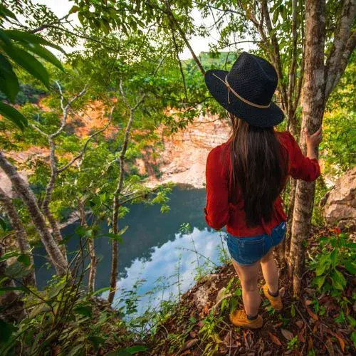 Visitante observando el Cenote Poza del Macho entre la vegetación