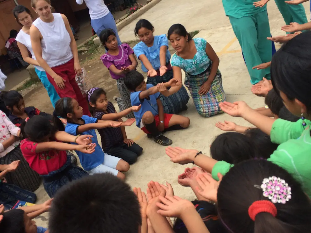 Niñas y niños de una escuela rural sentados en círculo en el patio durante una actividad sobre nutrición