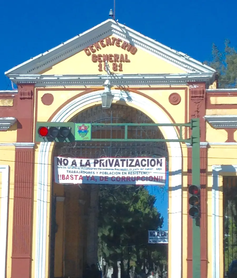 Pasillo del Cementerio General de Guatemala con mausoleos blancos a ambos lados y árboles al fondo