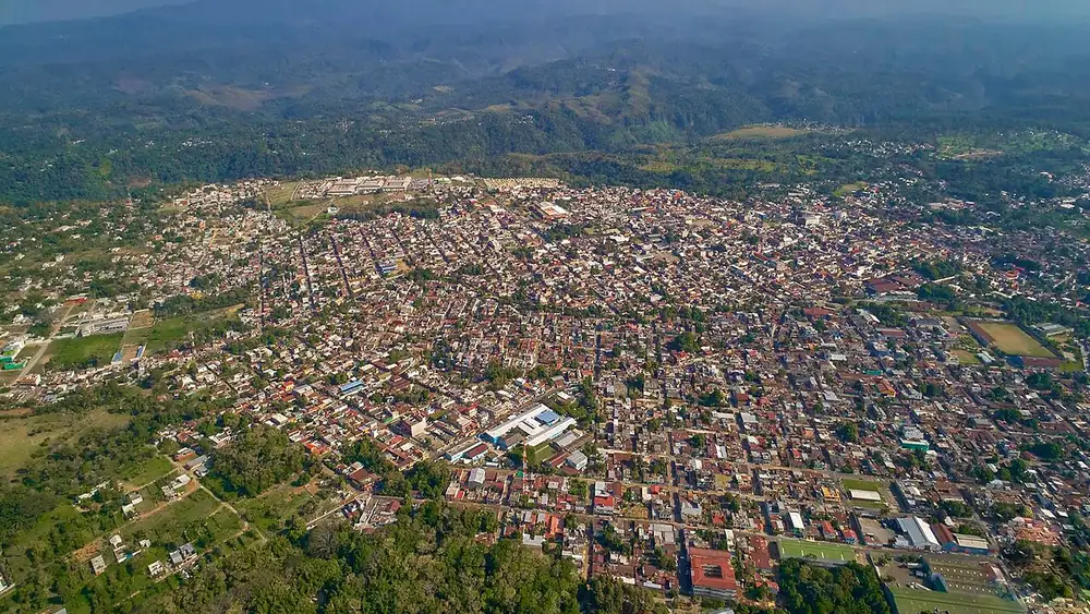 Vista aérea de la ciudad de Coatepeque, con casas de techo rojo y campos al fondo