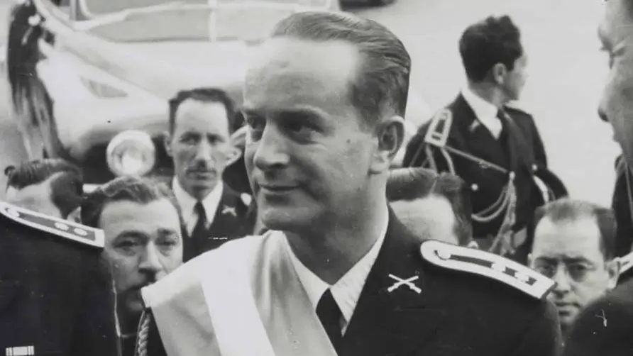 Jacobo Árbenz en blanco y negro, con uniforme militar y banda presidencial, rodeado de personas