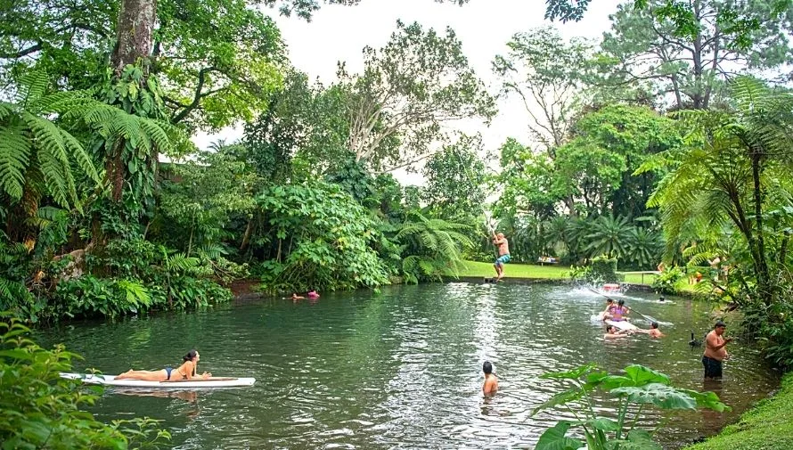 Personas disfrutando una poza natural rodeada de jardines en Finca El Zapote