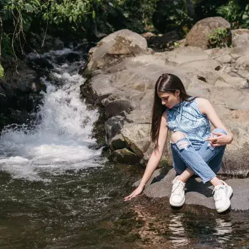 Visitante junto a la corriente de agua de la cascada La Escondida