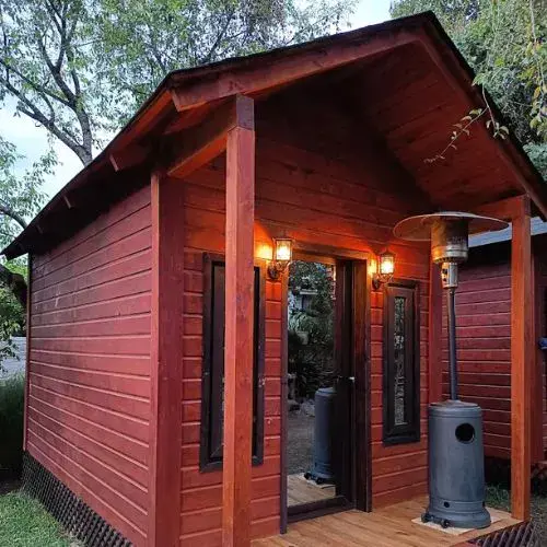 Cabaña de madera con calentador en el pórtico de Glamping de los Abuelos