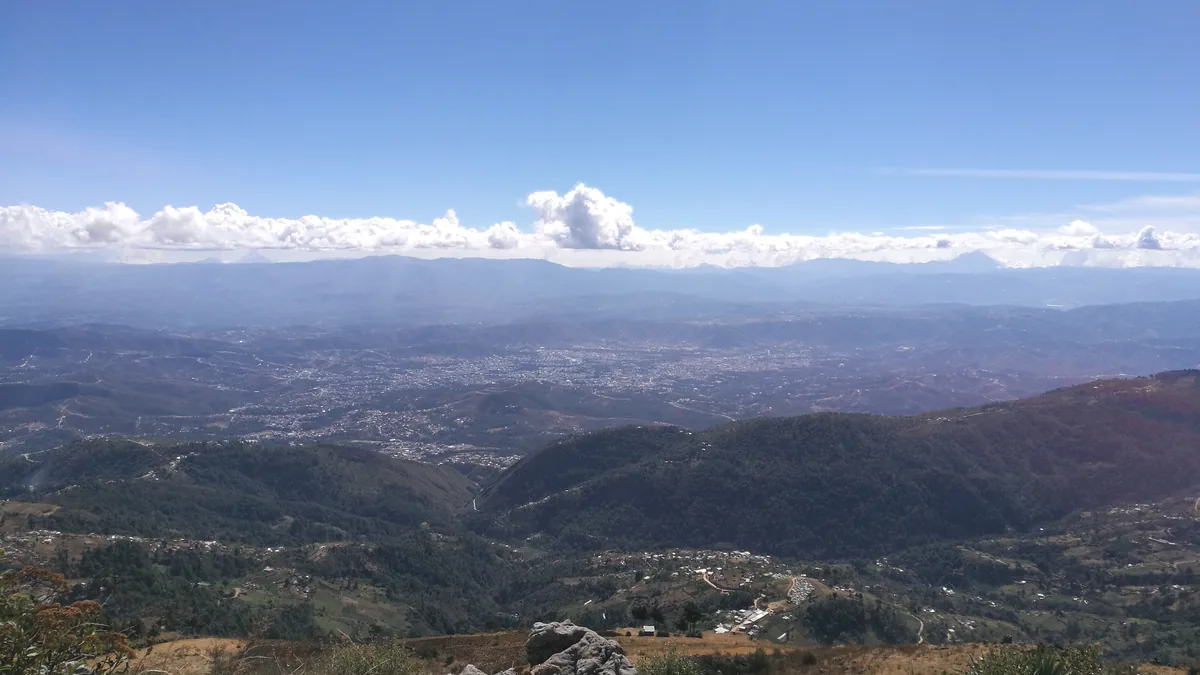 Valles y montañas vistos desde la Sierra de los Cuchumatanes, con cielo azul y nubes bajas