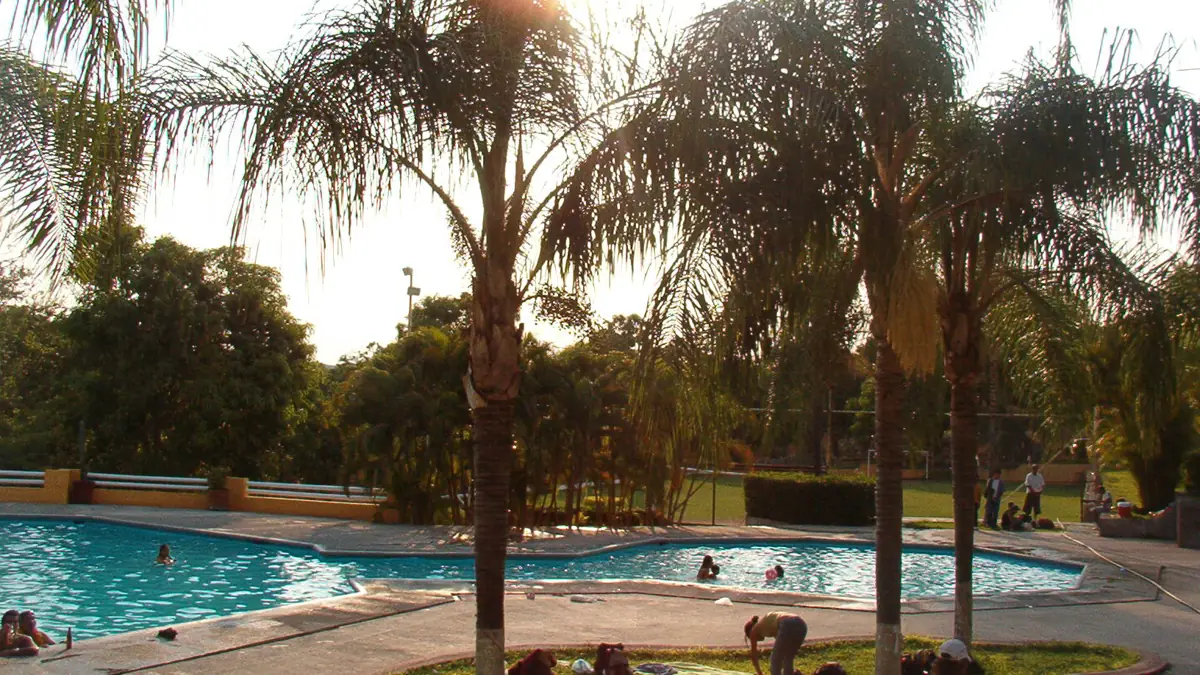 Piscinas de un balneario con palmeras altas al atardecer en Los Amates, Izabal
