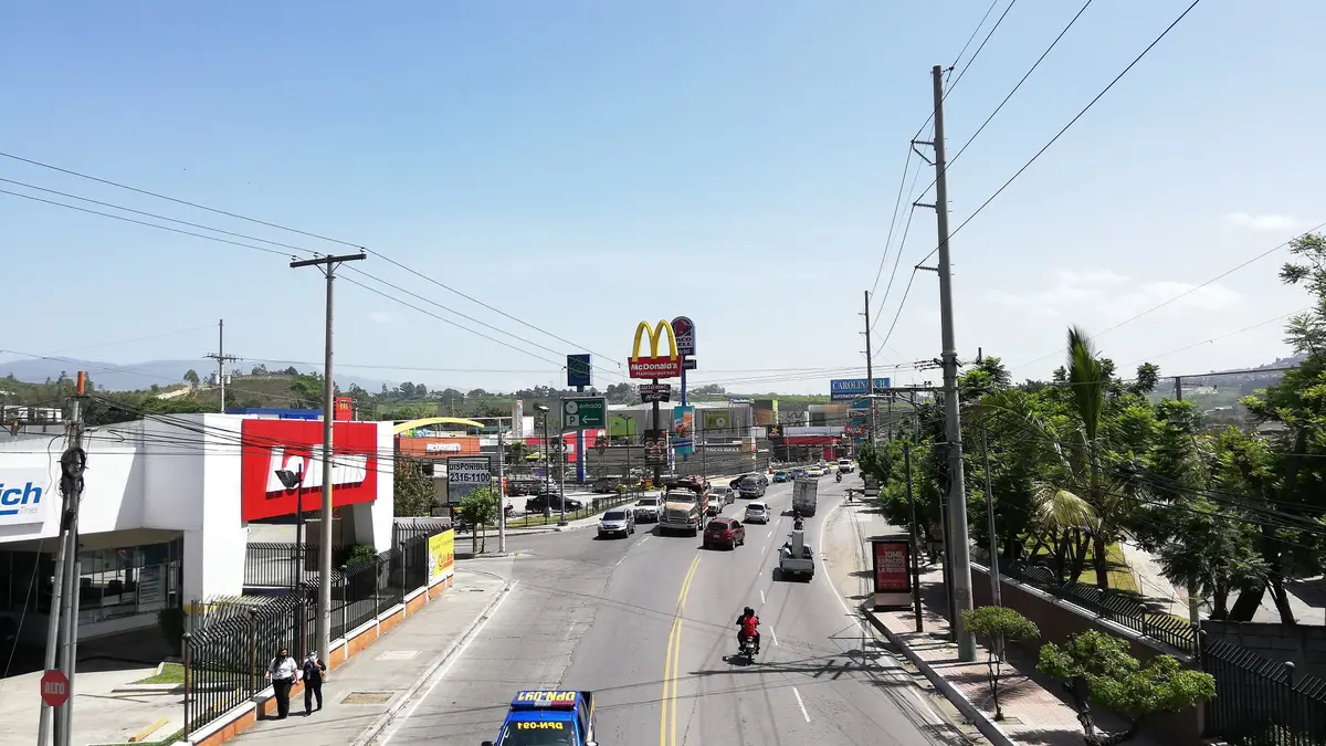 Bulevar El Frutal en la zona 5 de Villa Nueva, con tránsito de carros y motos, comercios y postes de luz a los lados
