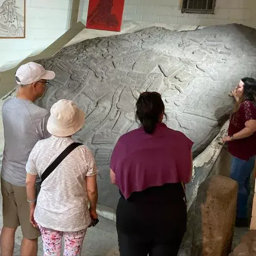 Visitantes observan un grabado arqueológico en el Museo Cultura Cotzumalguapa