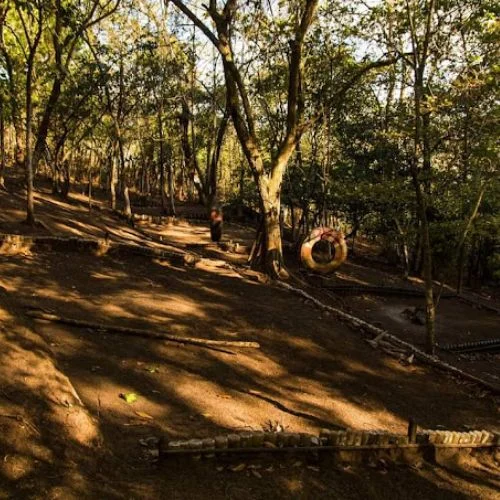 Área de juegos con columpio de llanta entre árboles del Parque Ecológico Xibalbá