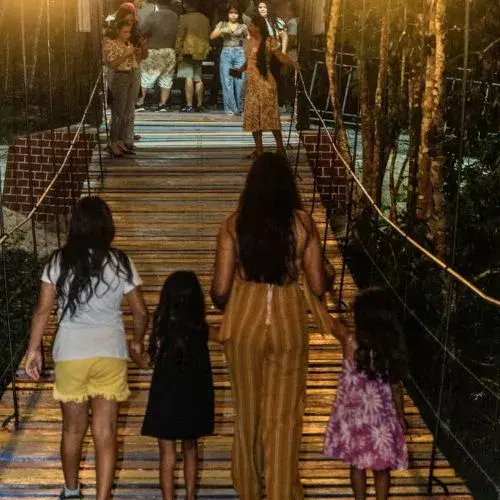 Familias caminan sobre el puente hamaca del Río Machaquilá