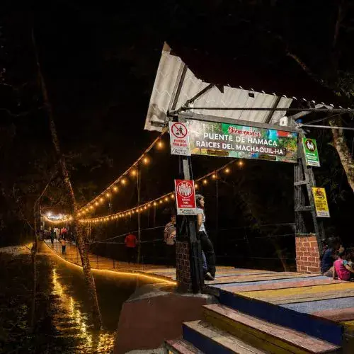 Puente hamaca iluminado sobre el Río Machaquilá durante la noche