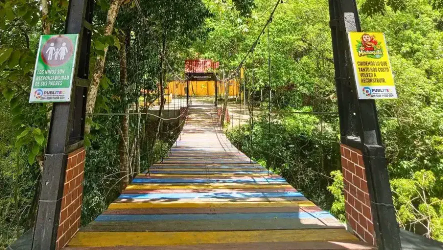 Puente hamaca con tablas de colores sobre el Río Machaquilá en Petén