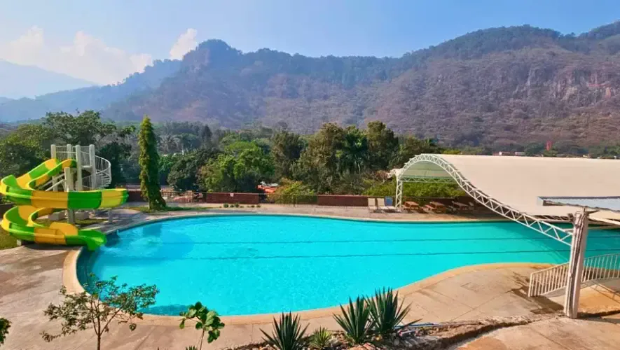 Piscina de El Rocarena con toboganes y montañas de Amatitlán al fondo