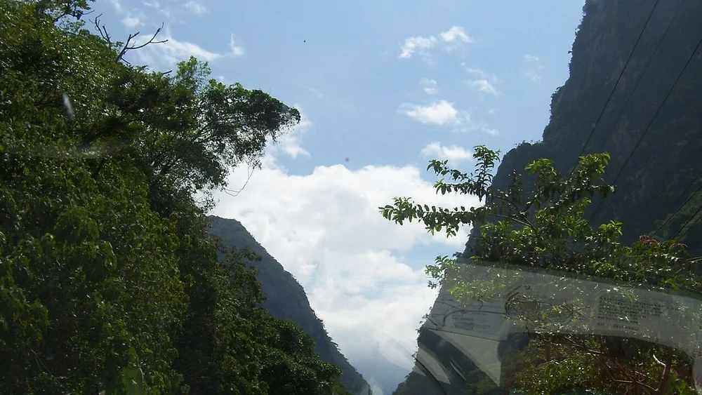 Carretera curva con barandal metálico bajo cerros secos y cielo azul en Huehuetenango
