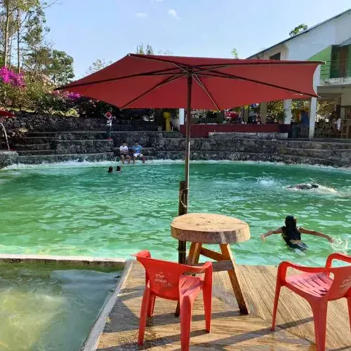 Piscina de Turicentro Chapac con sombrilla, sillas y áreas de descanso