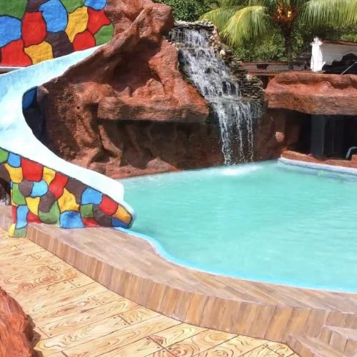 Tobogán y cascada decorativa sobre una piscina del Turicentro La Cascada