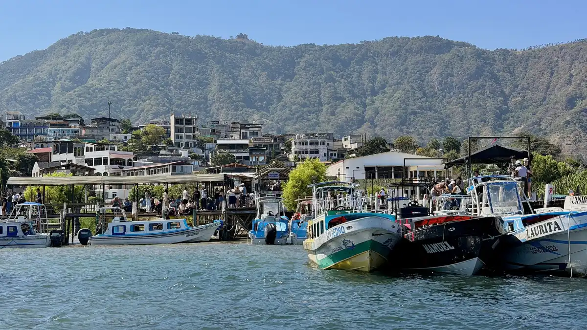 Muelle de San Juan La Laguna con lanchas de colores en el lago de Atitlán y cerros verdes al fondo