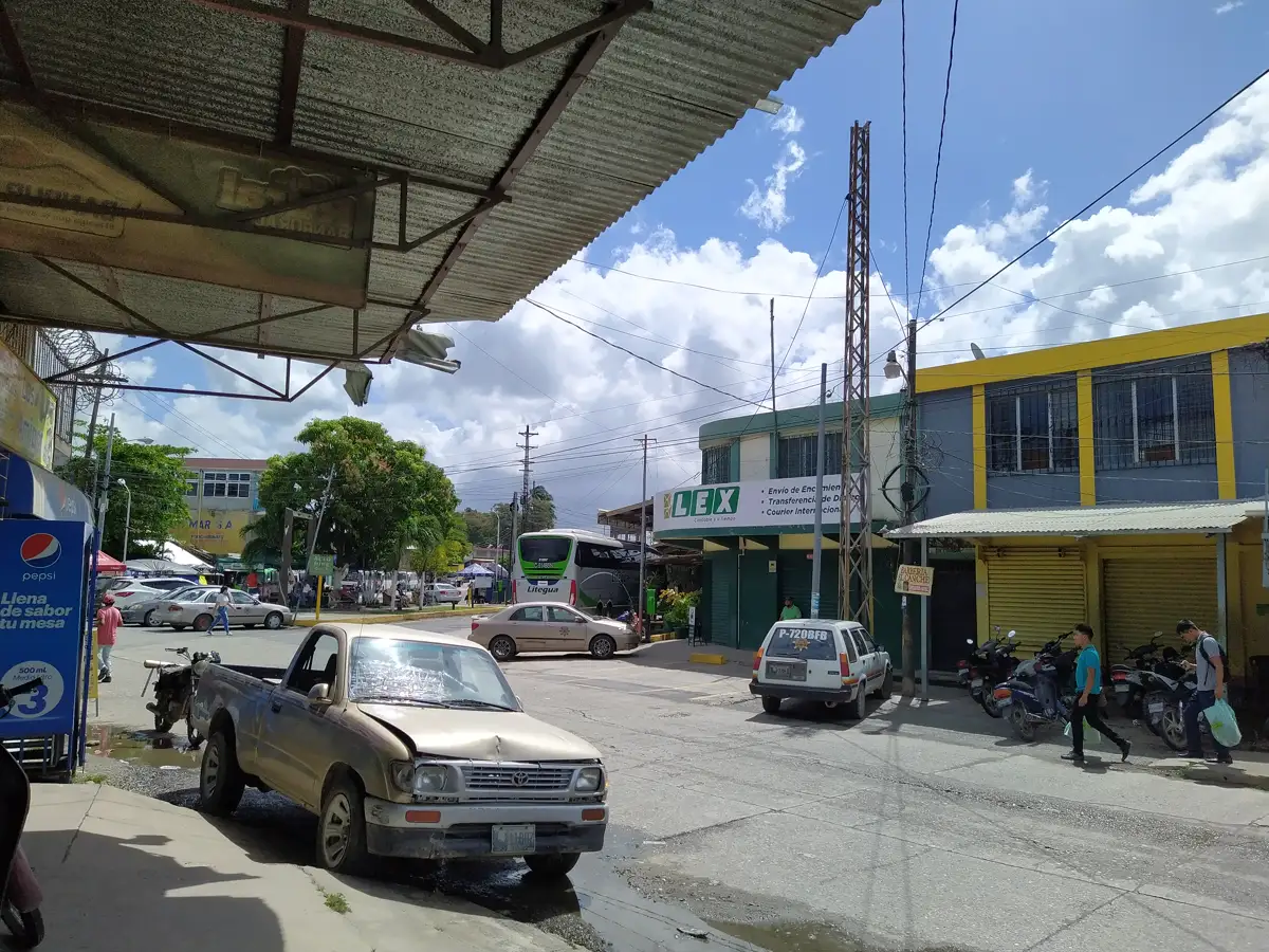 Calle del centro de Puerto Barrios con edificios de uno y dos pisos, vehículos estacionados y cielo despejado