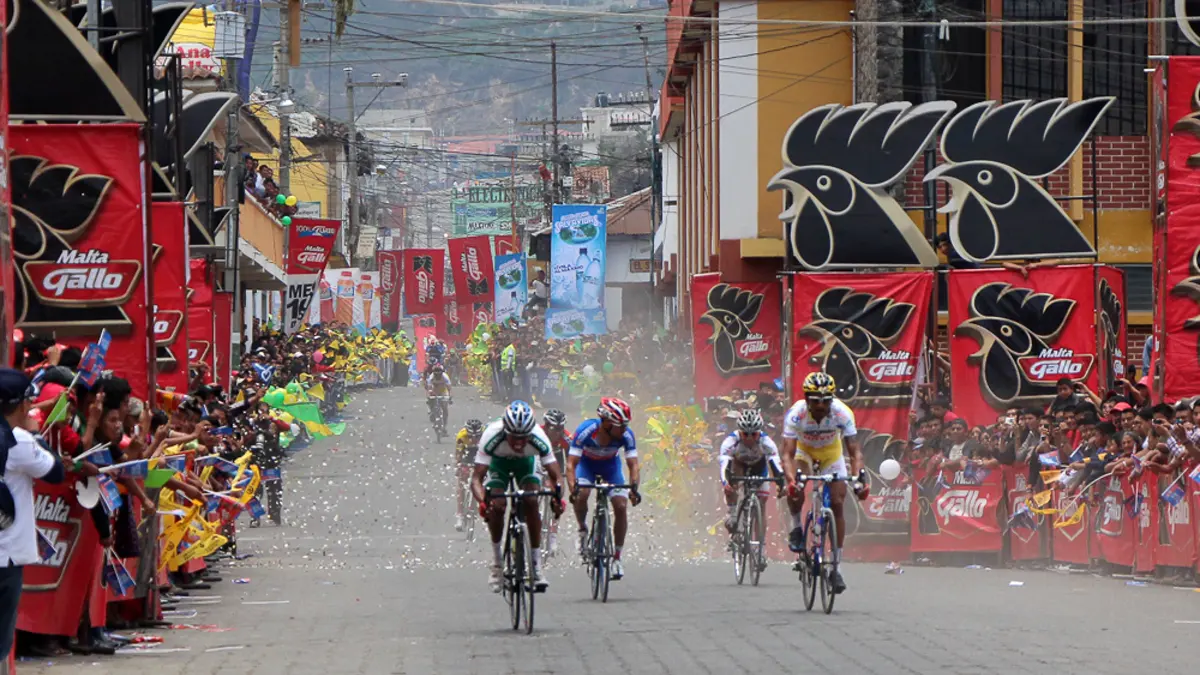 Ciclistas disputan el sprint final de una etapa de la Vuelta a Guatemala en una calle de Sololá, con público tras las vallas