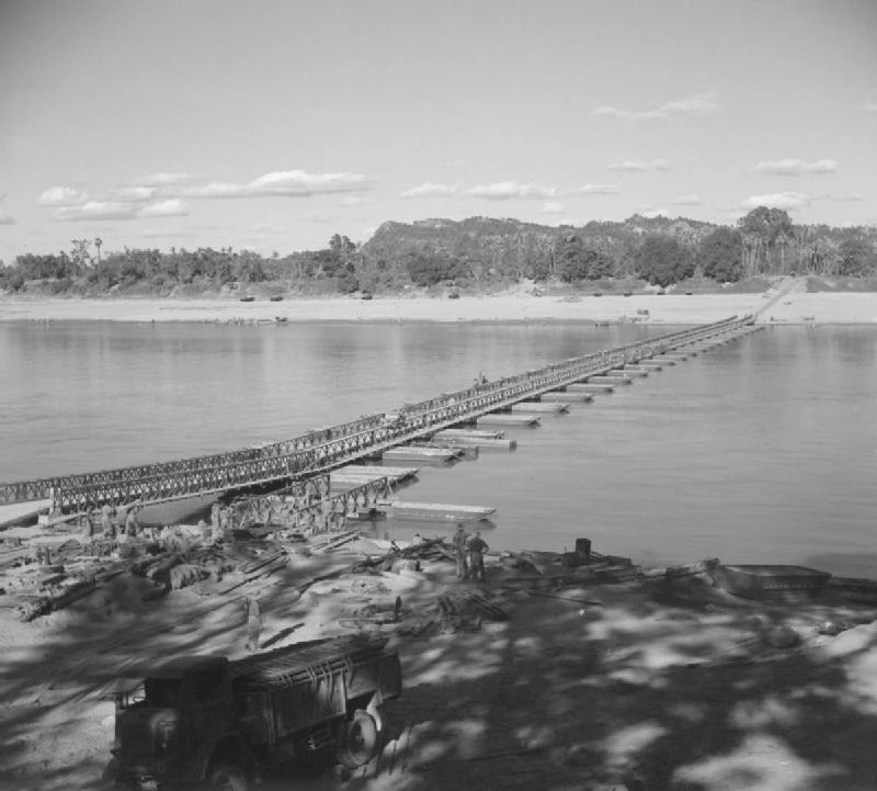 Puente Bailey tendido sobre el río Chindwin, en Birmania, con camiones y soldados en la orilla