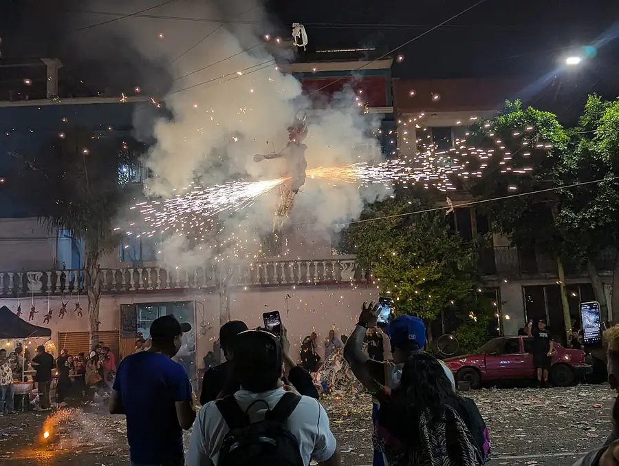 Muñeco de Judas que se quema de noche, con chispas y humo alrededor