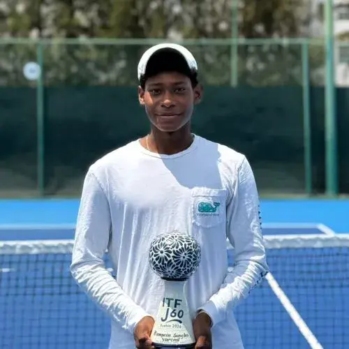 Ronaldo Cotom sostiene el trofeo del torneo individual J60 en una cancha de tenis
